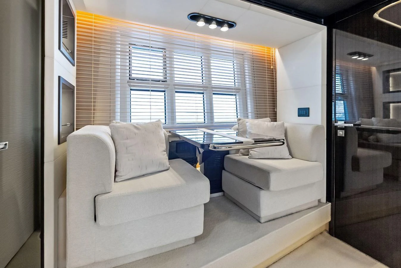 The yacht's interior features a cozy seating area with plush cushions and a modern table, bathed in natural light from large windows. aboard PANDA Yacht for Sale