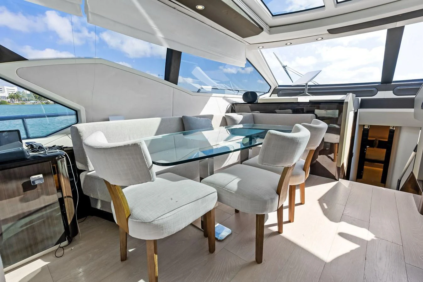 The yacht's dining area features a modern glass table surrounded by plush chairs, with ample natural light streaming through large windows. aboard PANDA Yacht for Sale