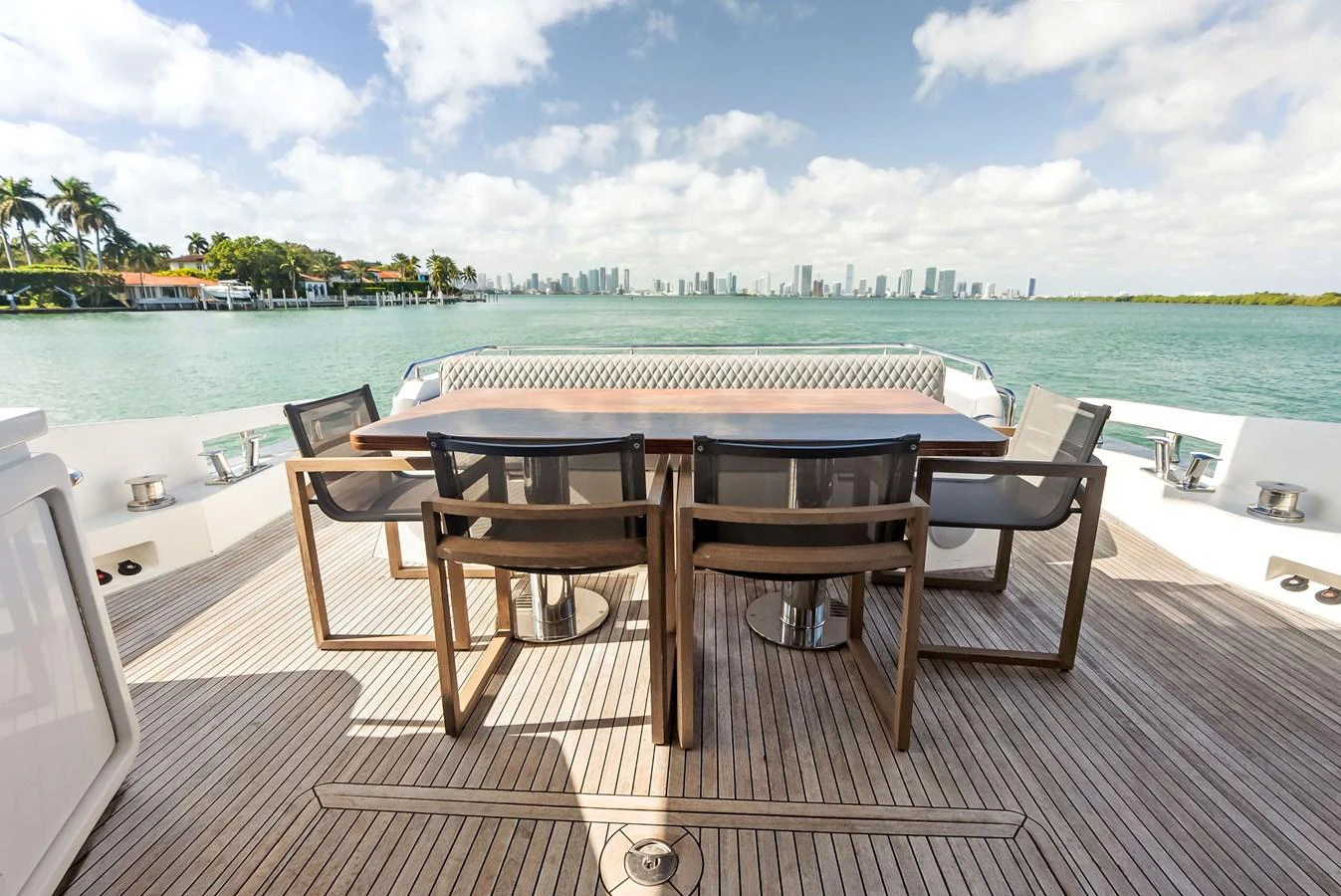The aft deck features a spacious dining area with a stunning view of the water and city skyline. aboard PANDA Yacht for Sale