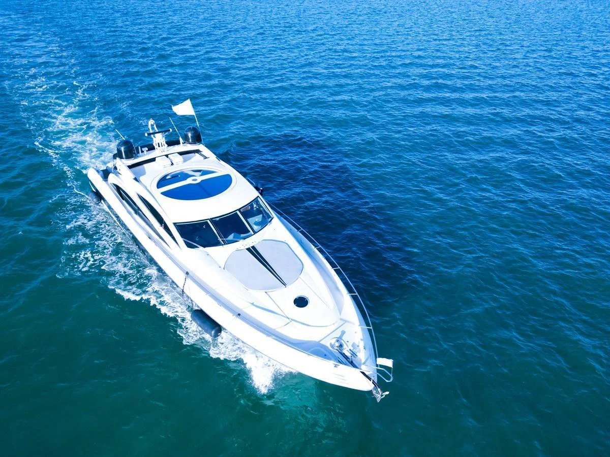 A sleek yacht cruises through clear blue waters, showcasing its modern design. aboard THE GAMBLER Yacht for Sale