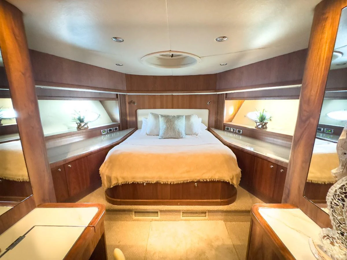 The master stateroom features a spacious bed with elegant wooden accents and ample lighting. aboard THE GAMBLER Yacht for Sale