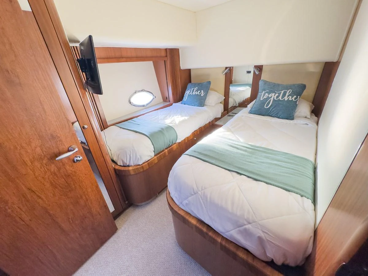 The twin stateroom features two comfortable single beds with elegant bedding and a cozy atmosphere. aboard THE GAMBLER Yacht for Sale