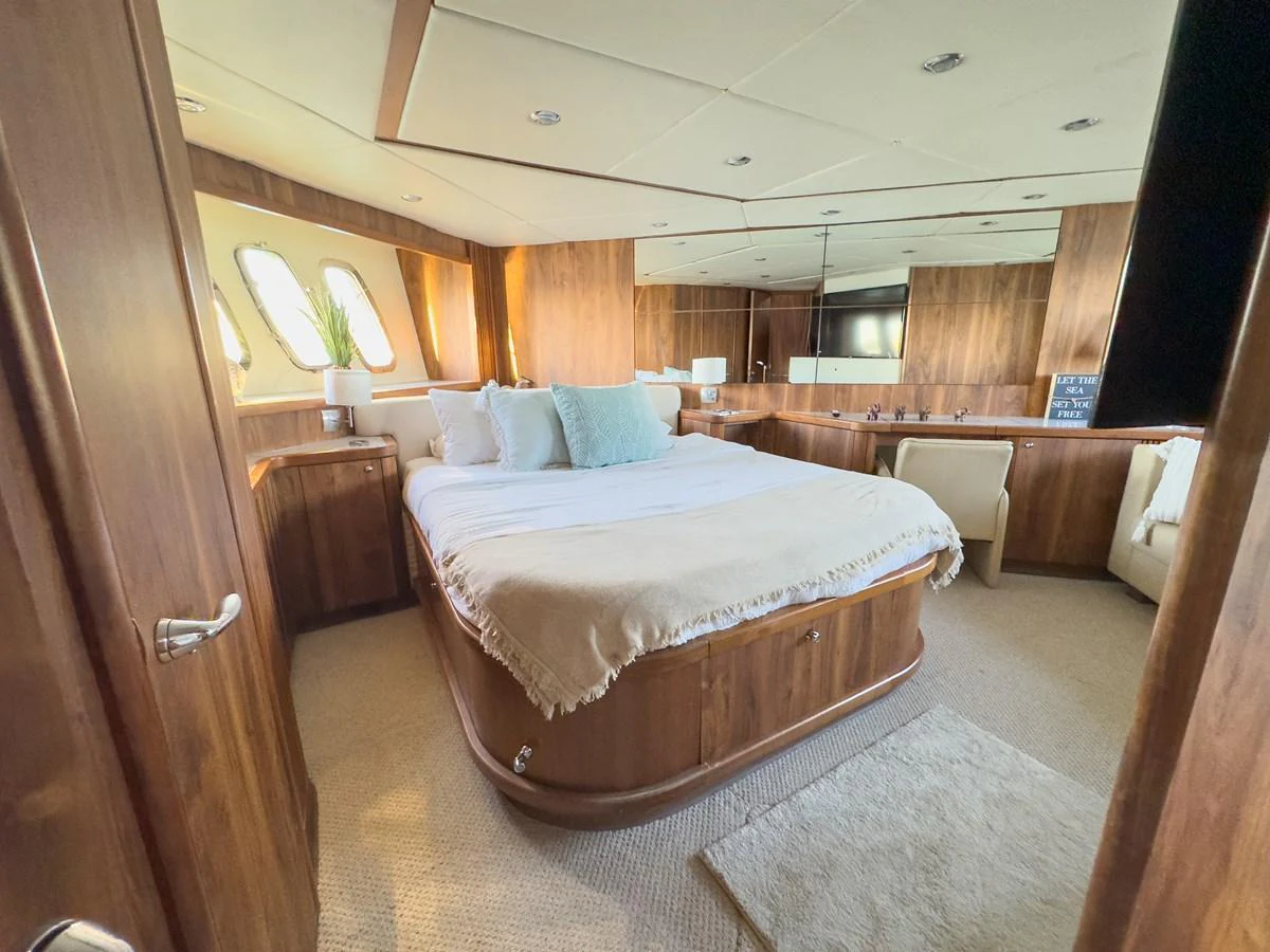 The master stateroom features a spacious bed with elegant wooden paneling and ample natural light. aboard THE GAMBLER Yacht for Sale