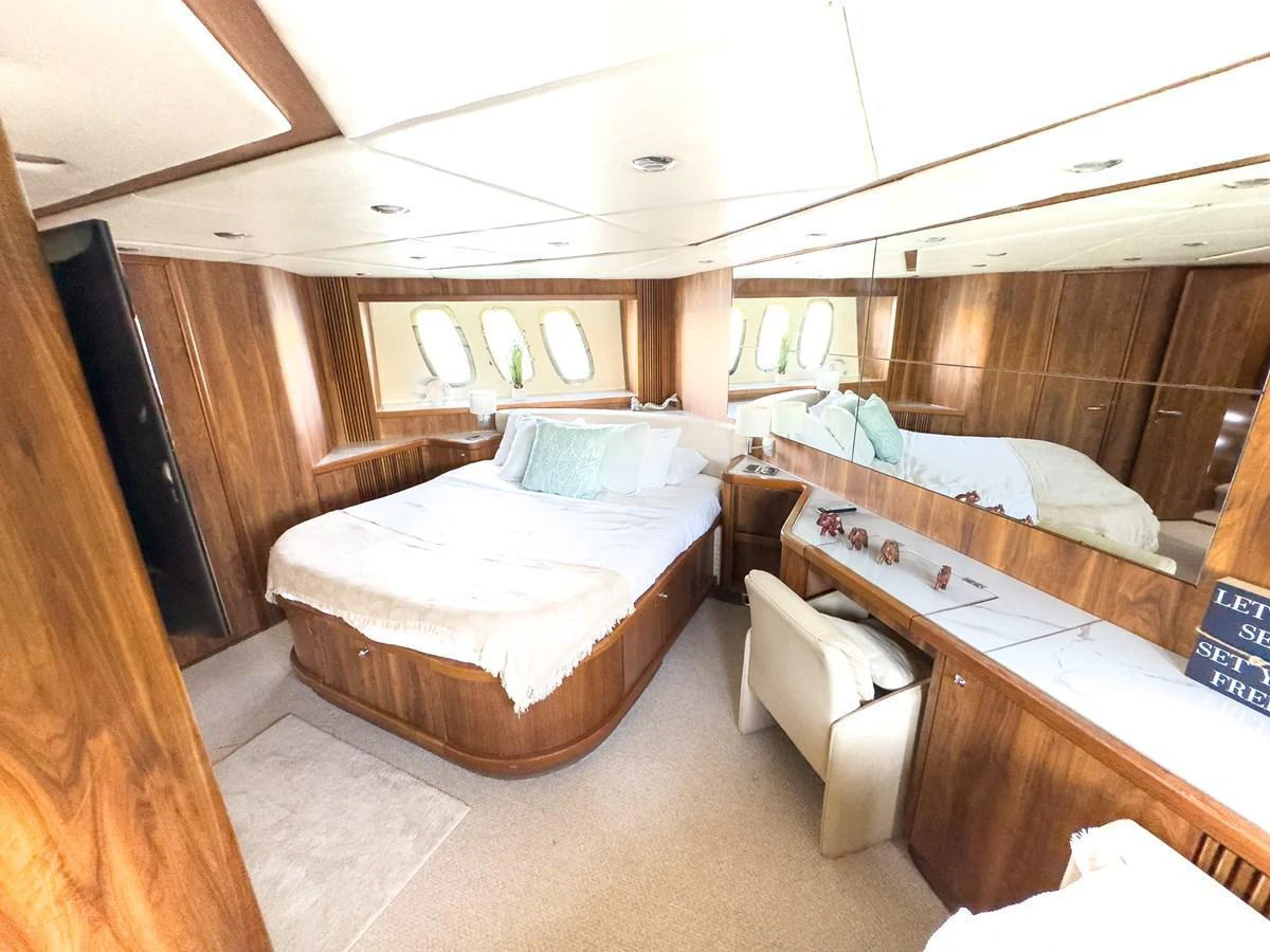 The stateroom features a comfortable bed with elegant wood paneling and ample natural light. aboard THE GAMBLER Yacht for Sale