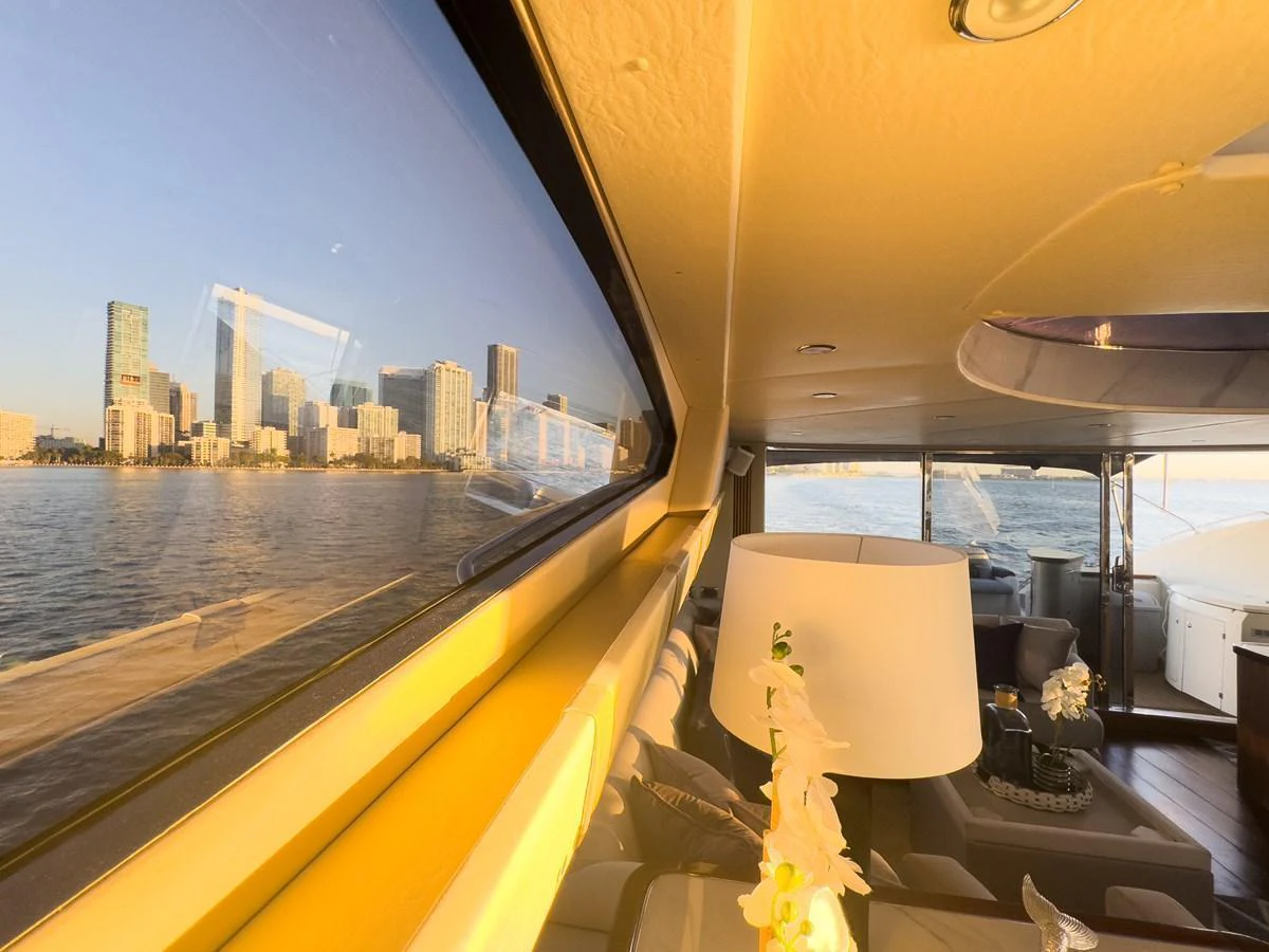 The yacht's interior offers a cozy and elegant space with a stunning view of the city skyline through large windows. aboard THE GAMBLER Yacht for Sale