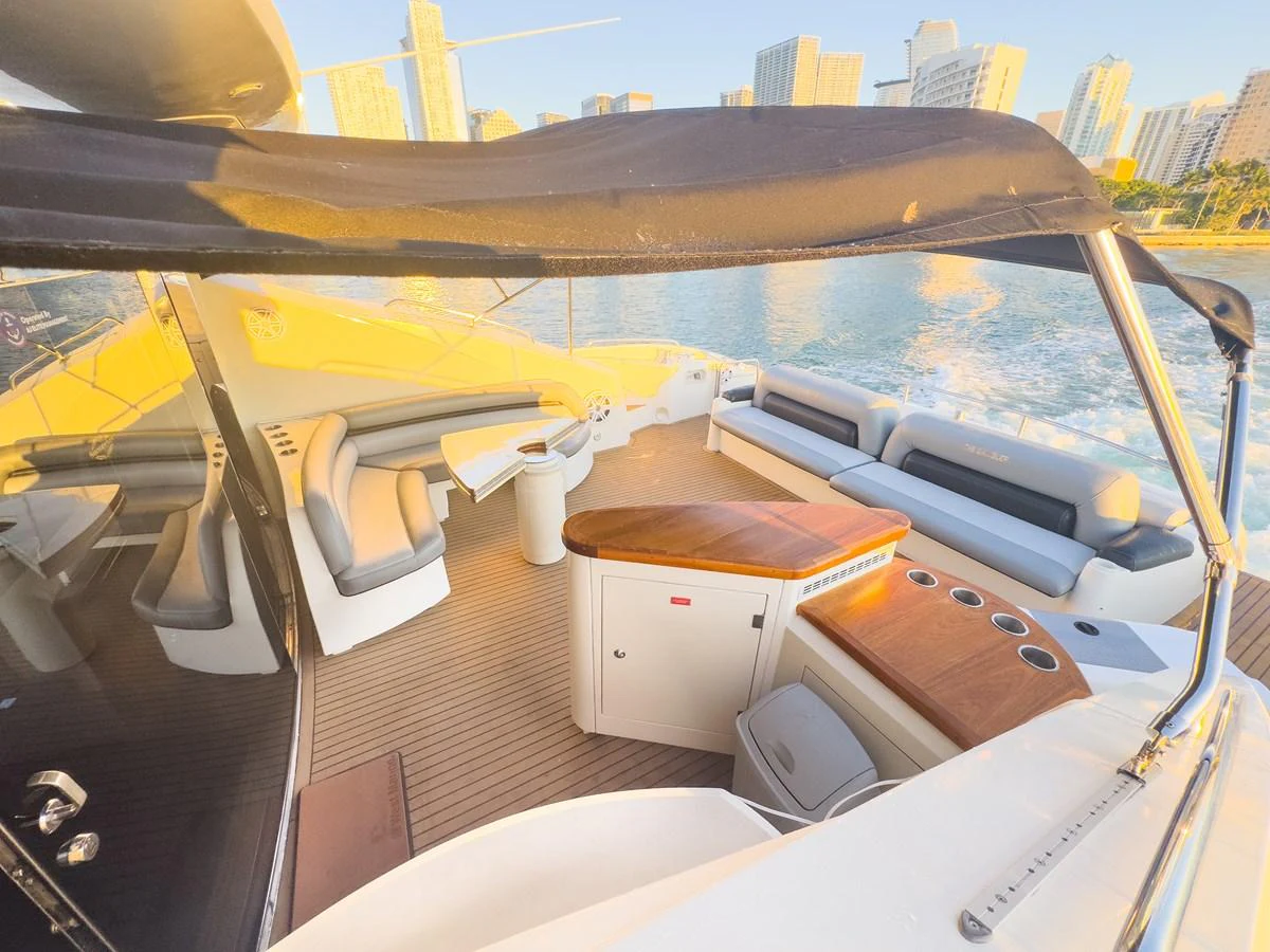 The aft deck features a spacious seating area with a wooden table and a wet bar, perfect for entertaining while enjoying the view. aboard THE GAMBLER Yacht for Sale