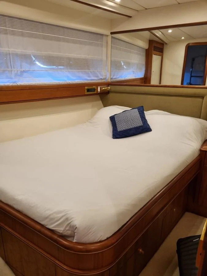 a bed with a white sheet and blue pillow on it aboard LADY AMANDA Yacht for Sale