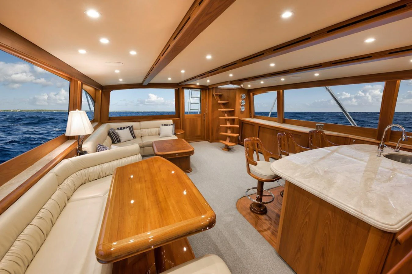 The salon features plush seating, a dining area, and panoramic windows offering stunning ocean views. aboard BREE Yacht for Sale