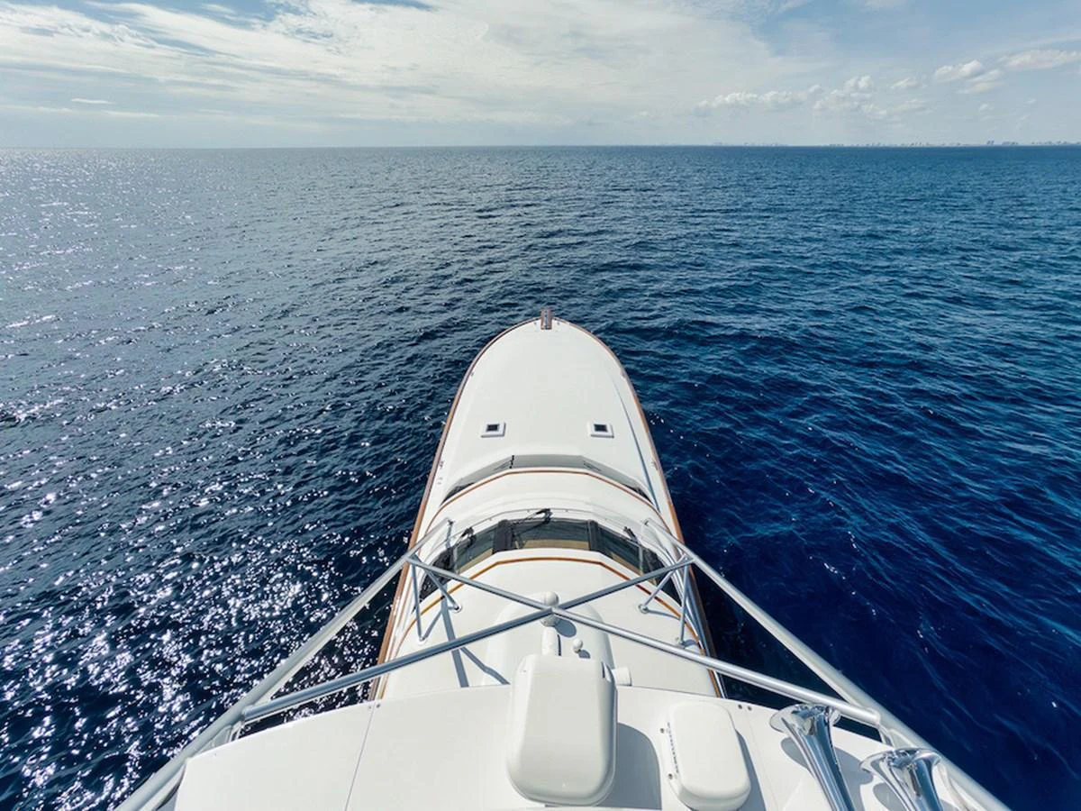 The yacht's bow cuts through the serene, deep blue ocean under a clear sky. aboard BREE Yacht for Sale