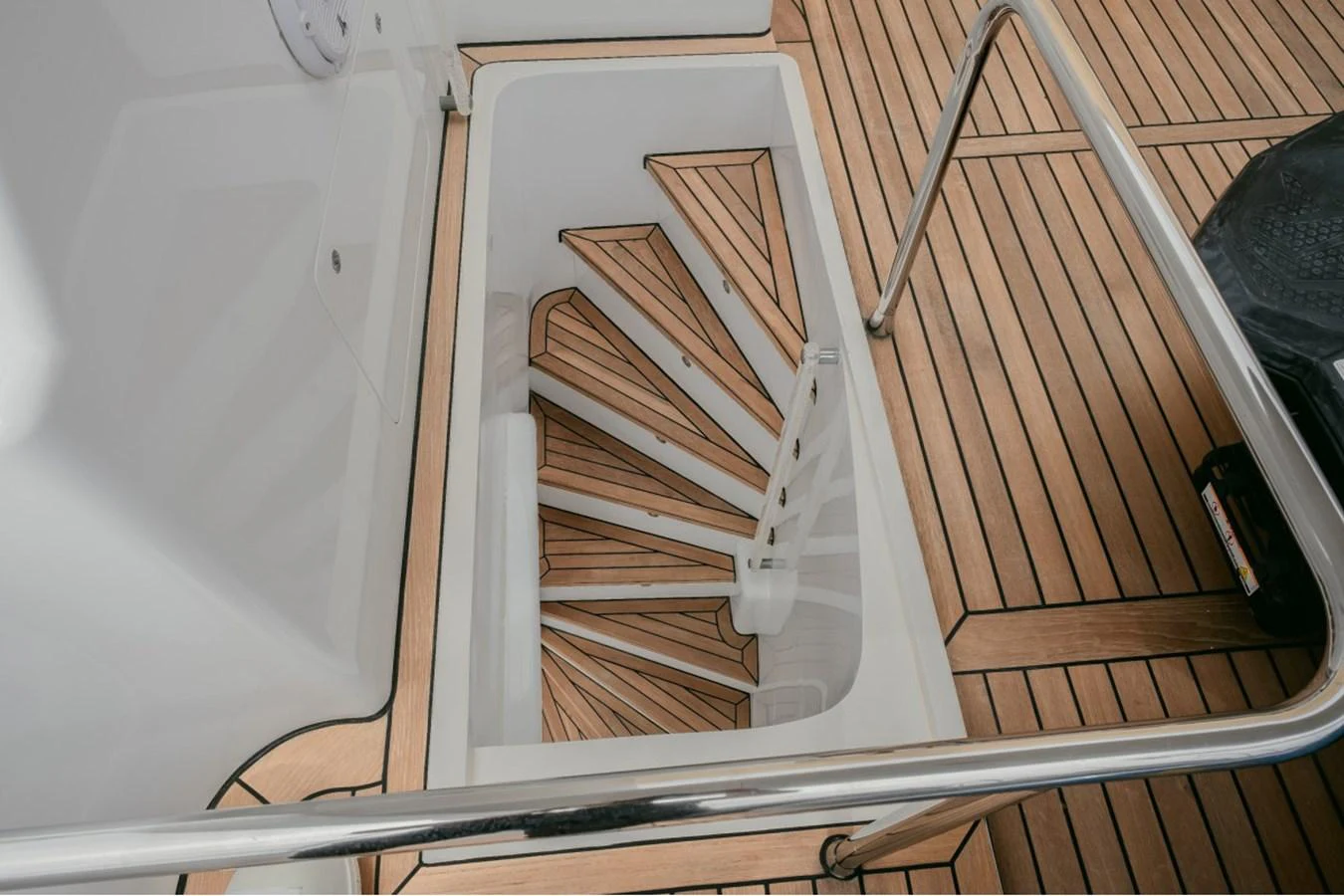 A stylish spiral staircase leads down from the deck, showcasing elegant wood and metal finishes. aboard PARSLEY Yacht for Sale