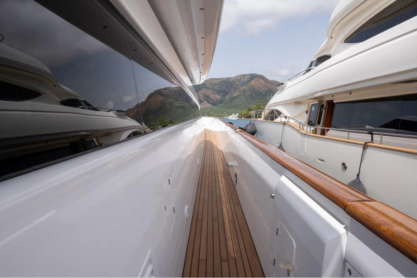 A sleek side deck with polished wood and reflective surfaces, offering a glimpse of the surrounding landscape. aboard PARSLEY Yacht for Sale
