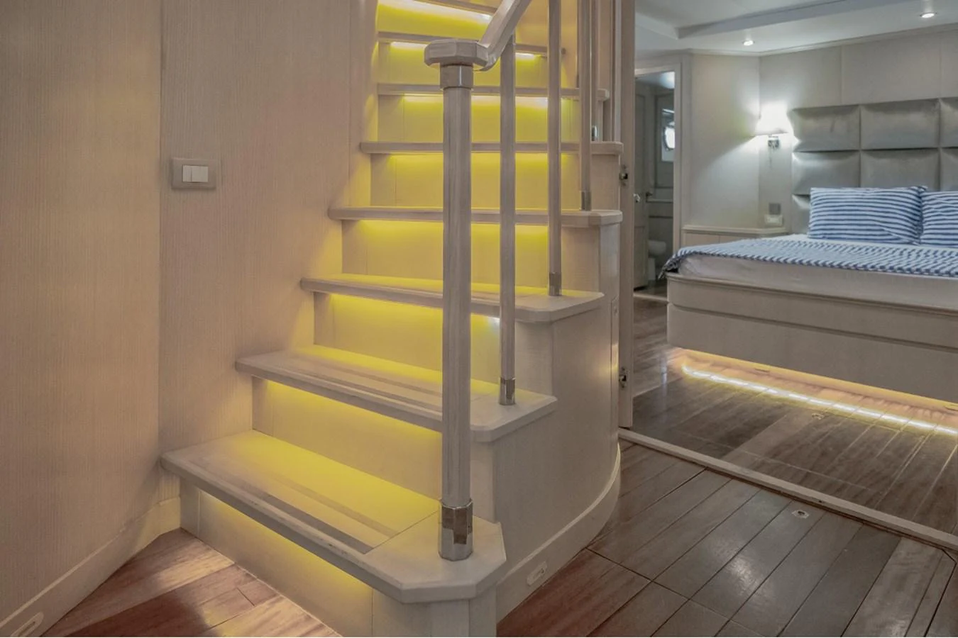 A luxurious interior featuring a softly lit staircase leading to a cozy bedroom with modern decor. aboard PARSLEY Yacht for Sale