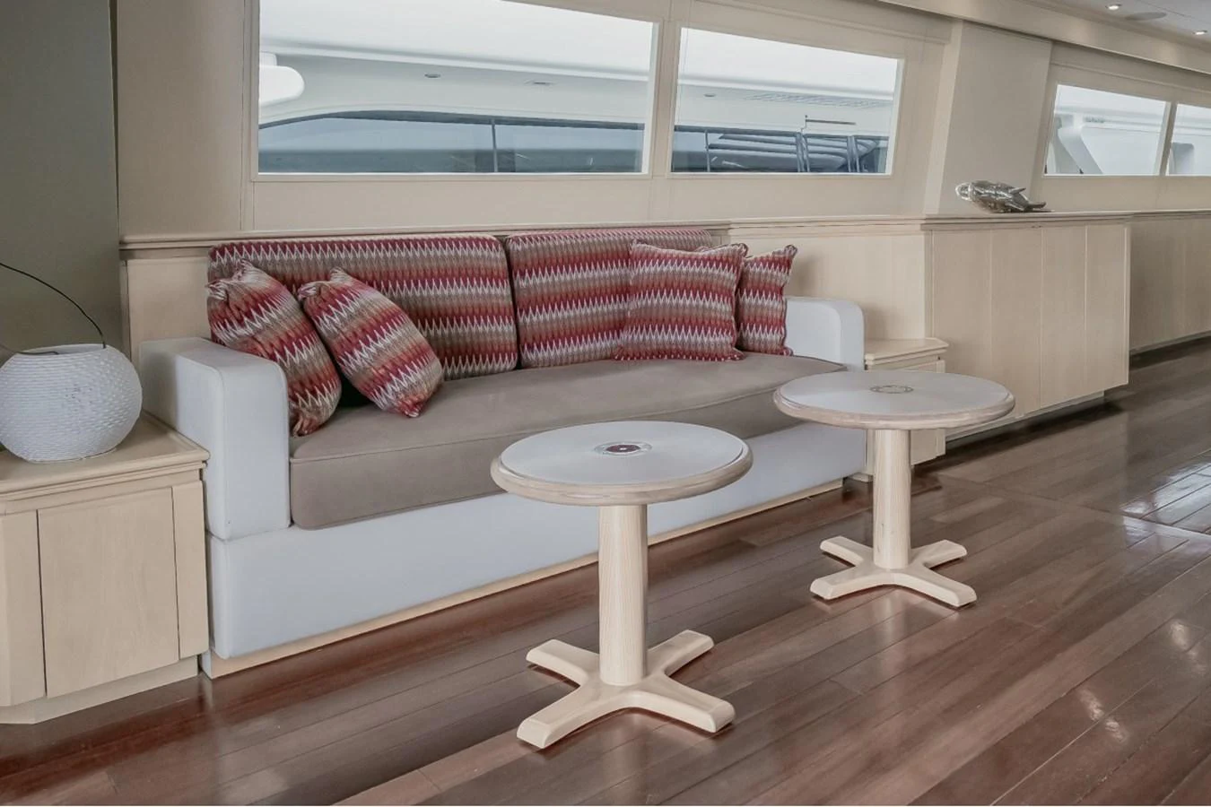 The yacht's interior features a cozy seating area with a modern sofa and stylish tables, complemented by large windows offering ample natural light. aboard PARSLEY Yacht for Sale