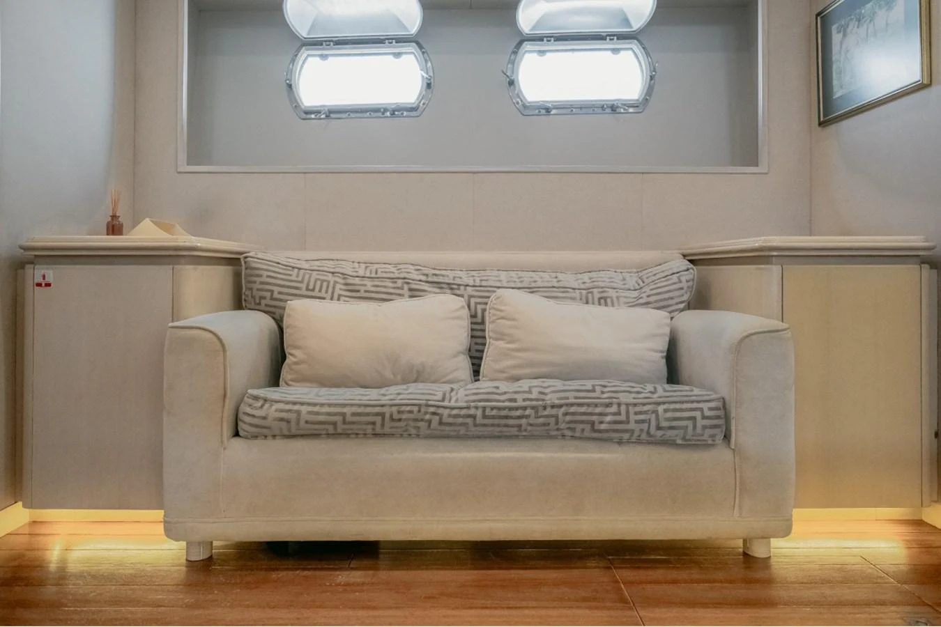 The cozy salon features a comfortable sofa beneath large windows, creating a bright and inviting space. aboard PARSLEY Yacht for Sale