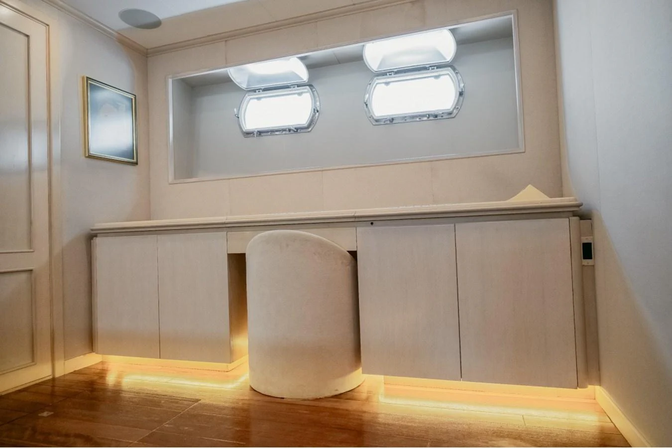 A serene interior space featuring a built-in desk with ambient lighting and porthole windows. aboard PARSLEY Yacht for Sale