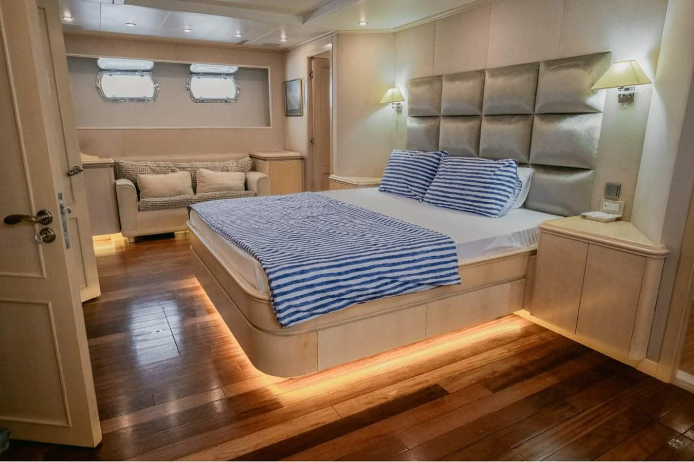 The master stateroom features a luxurious bed with striped bedding and ambient lighting. aboard PARSLEY Yacht for Sale