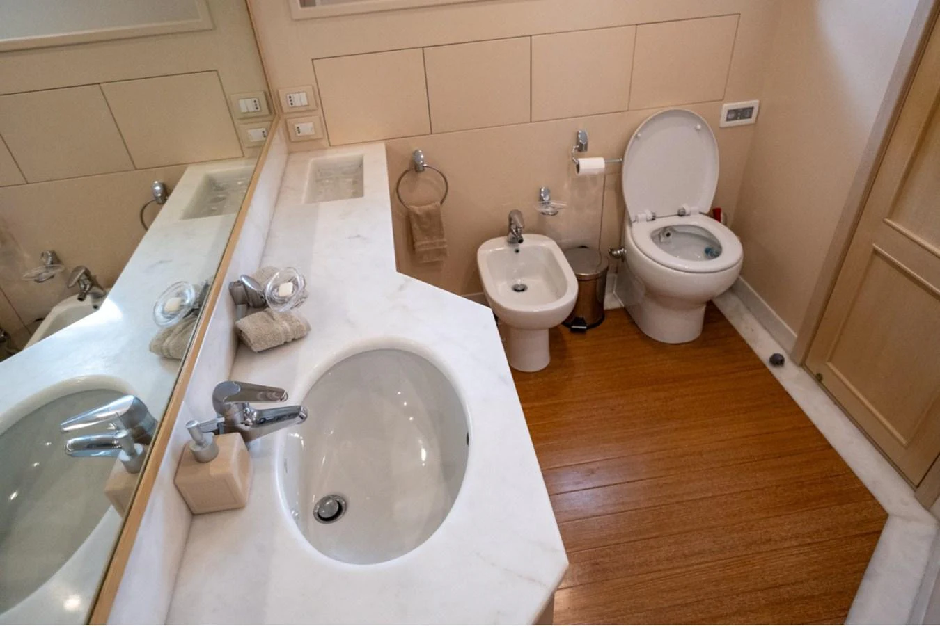 The yacht's bathroom features a sleek sink, a bidet, and a toilet, all set against a warm wooden floor. aboard PARSLEY Yacht for Sale