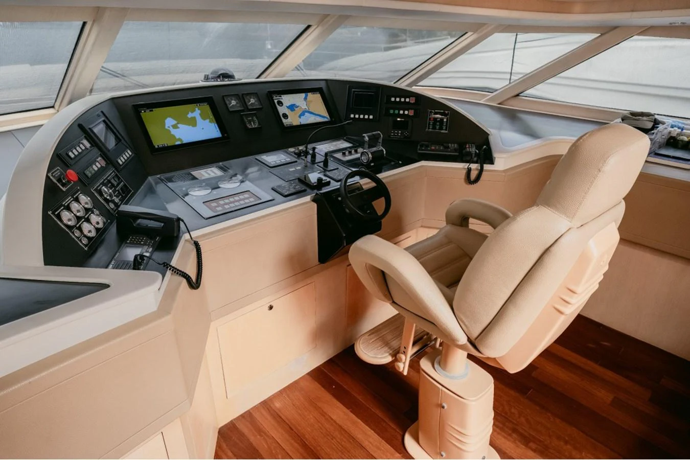 The helm station features advanced navigation equipment and a comfortable captain's chair, set against a backdrop of sleek wood flooring. aboard PARSLEY Yacht for Sale