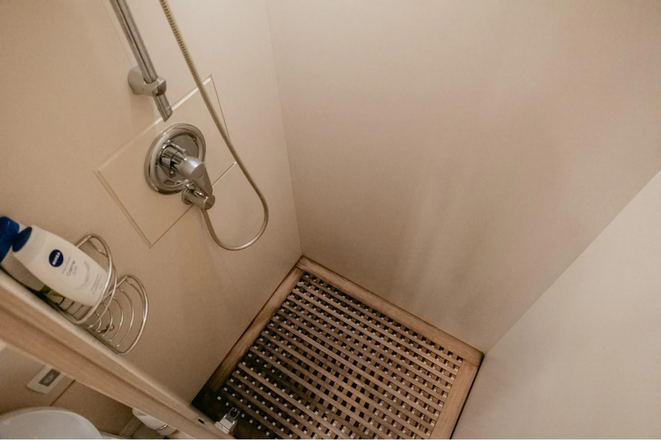 A compact and modern shower area with a wooden floor grate and a sleek shower fixture. aboard PARSLEY Yacht for Sale