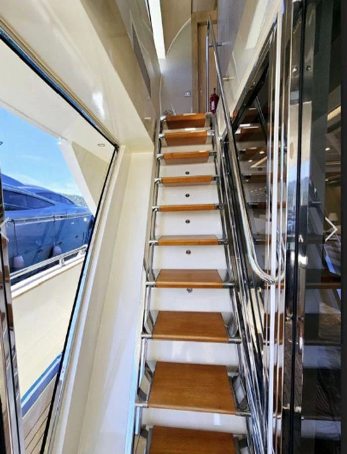 A sleek staircase with wooden steps and stainless steel railings leads to the upper deck. aboard RIVA 115 Yacht for Sale