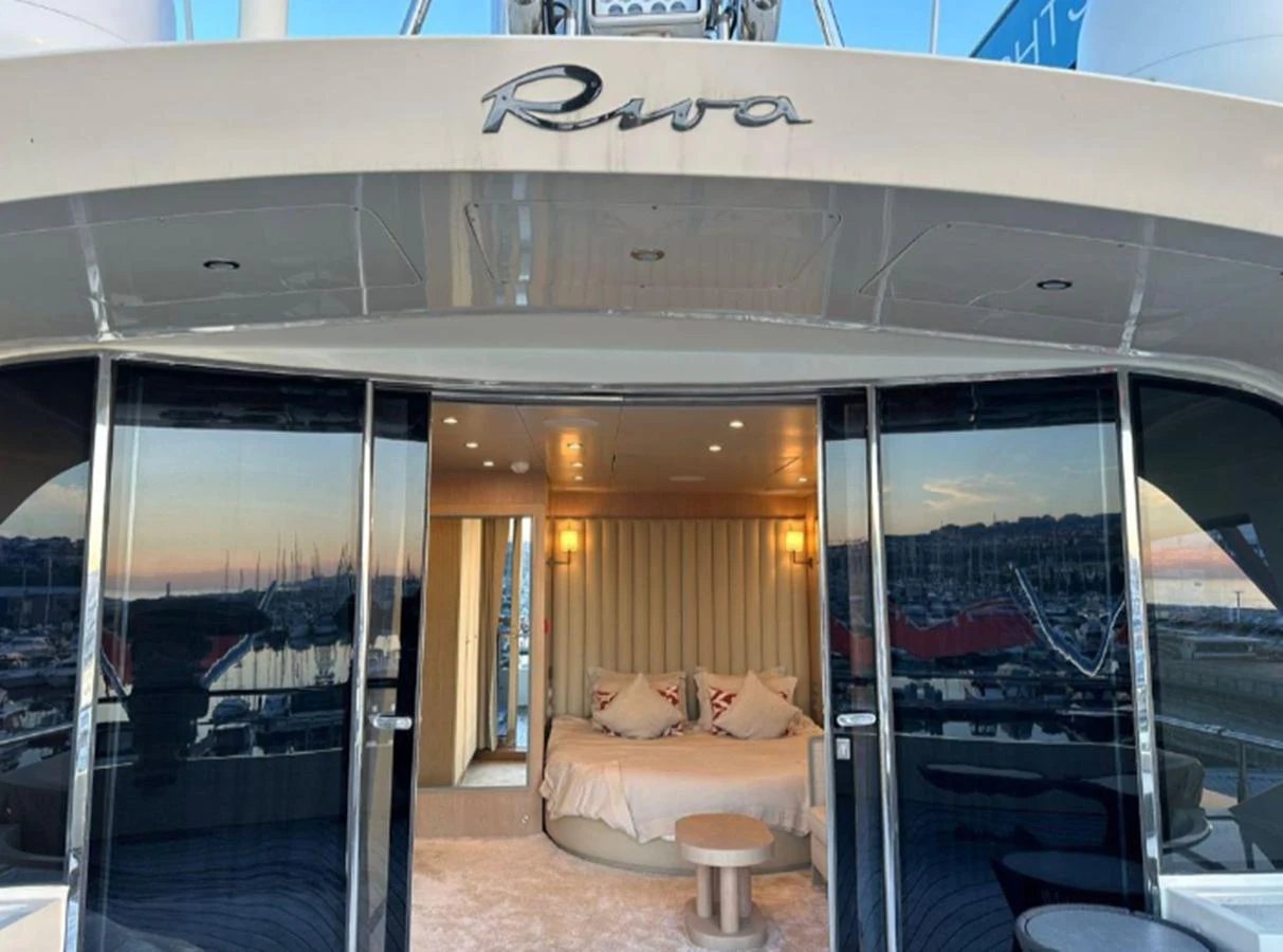 A cozy stateroom with a plush bed and elegant lighting, viewed from the aft deck. aboard RIVA 115 Yacht for Sale