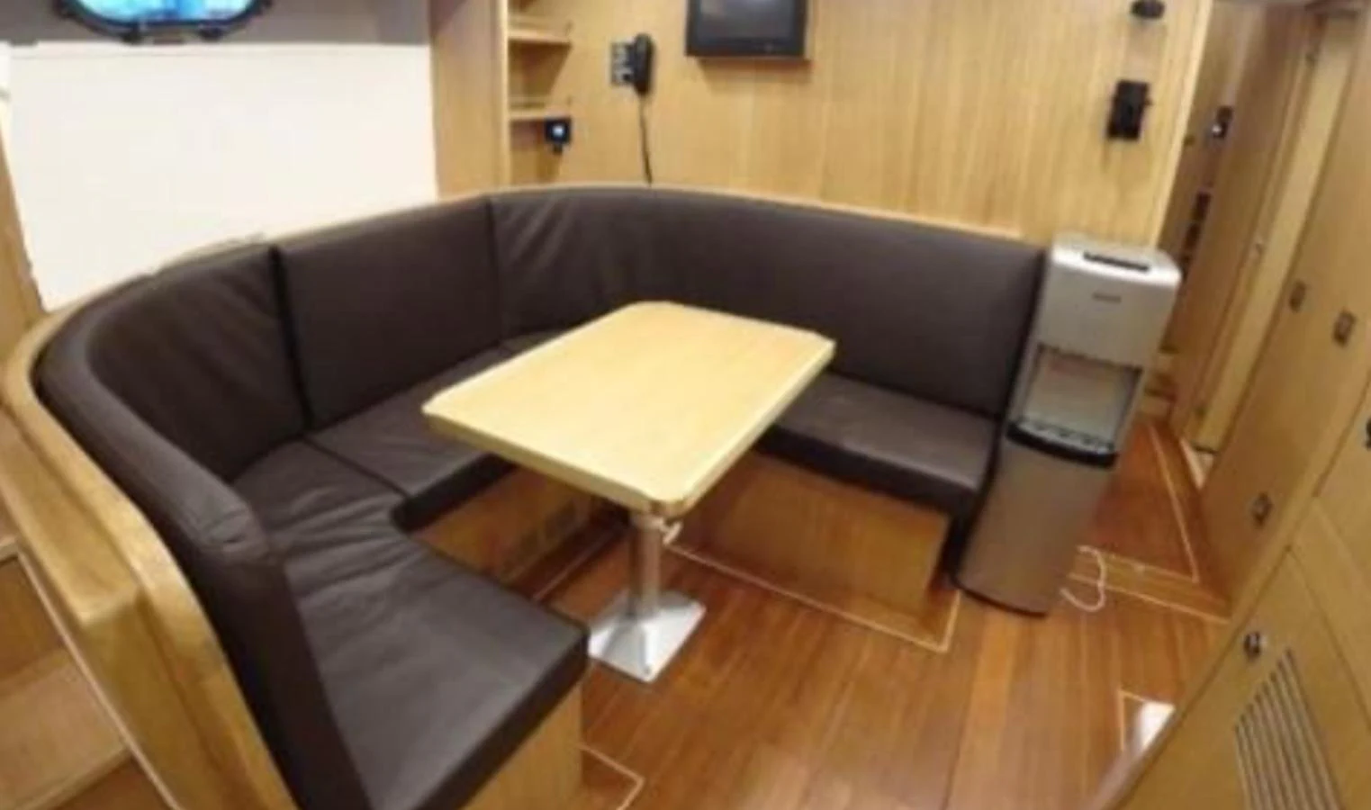 The yacht's interior features a cozy dining area with a wooden table and comfortable seating. aboard RIVA 115 Yacht for Sale