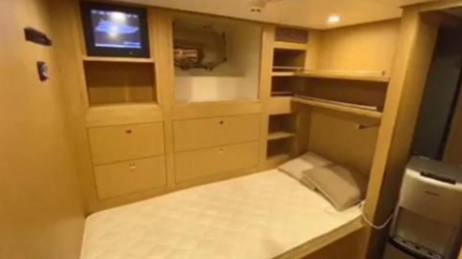 A cozy cabin with a single bed, built-in storage, and a television. aboard RIVA 115 Yacht for Sale