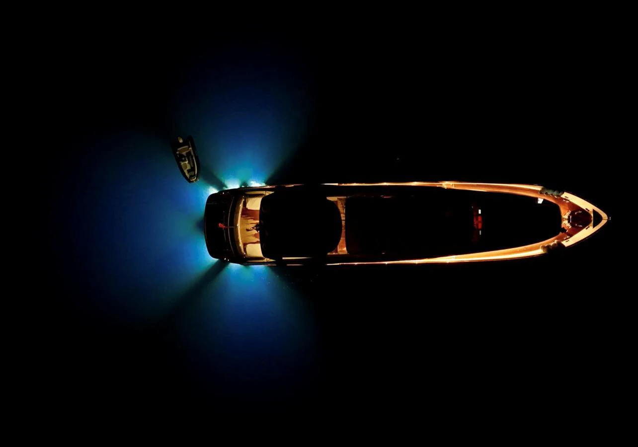 A yacht illuminated at night, viewed from above with surrounding water glowing from underwater lights. aboard RIVA 115 Yacht for Sale