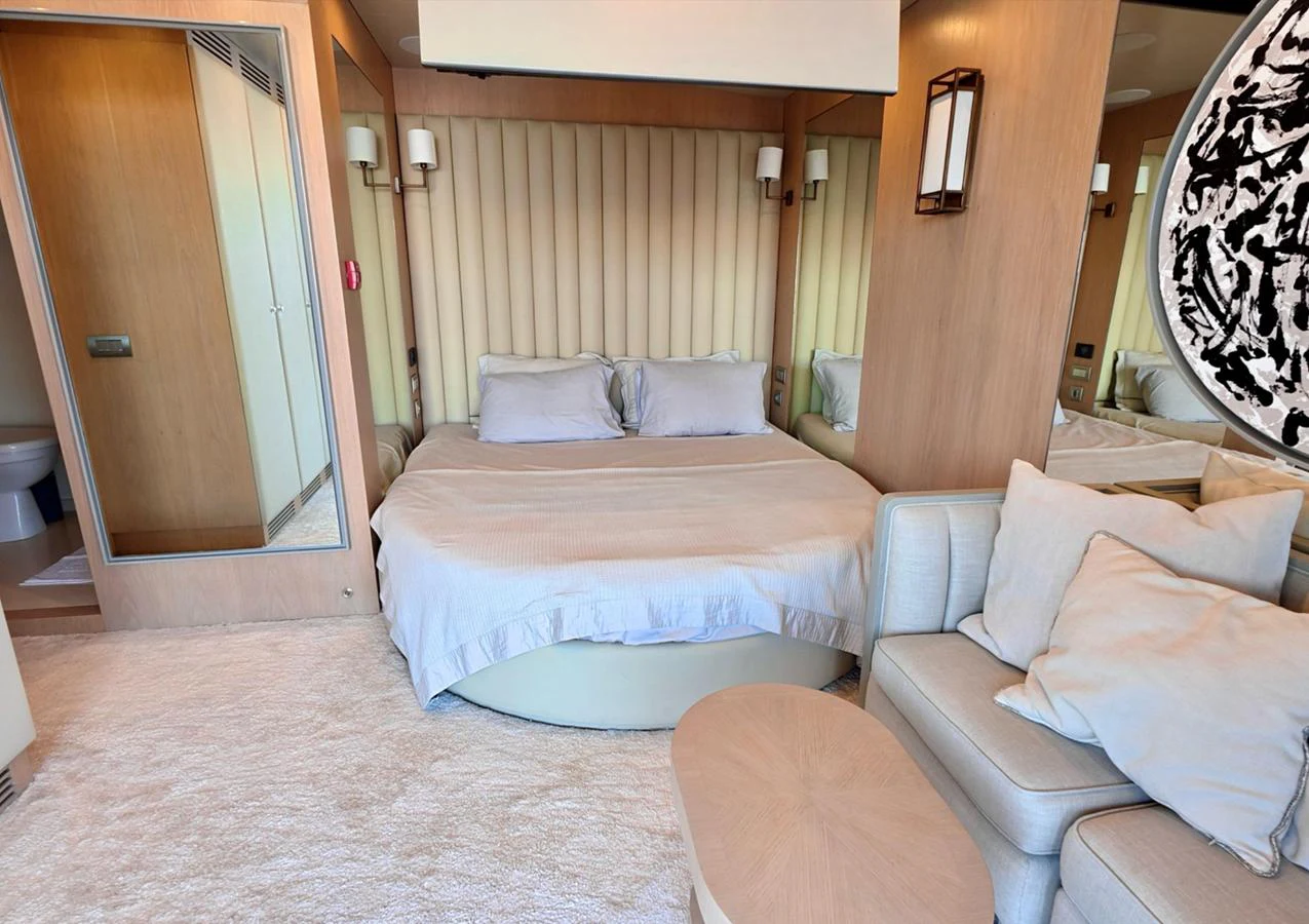 The stateroom features a plush bed with elegant bedding and a cozy seating area, creating a serene retreat. aboard RIVA 115 Yacht for Sale
