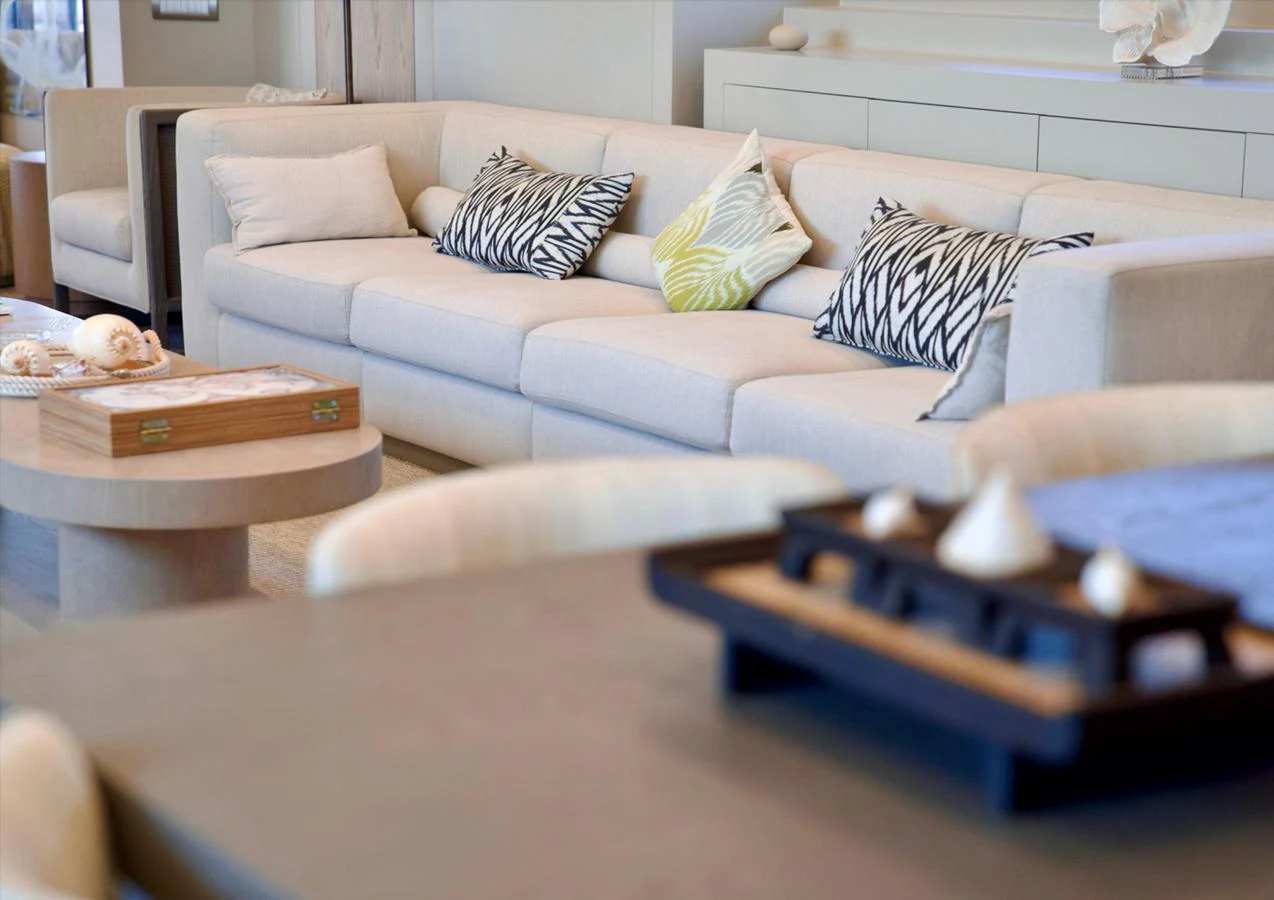 The salon features a plush, light-colored sofa adorned with patterned cushions, creating a cozy and inviting atmosphere. aboard RIVA 115 Yacht for Sale
