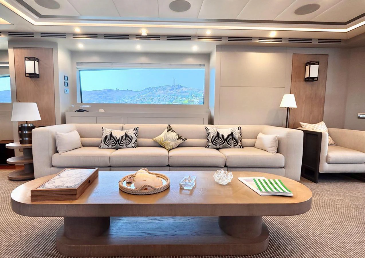 The salon features a spacious and elegant seating area with a large window providing scenic views. aboard RIVA 115 Yacht for Sale