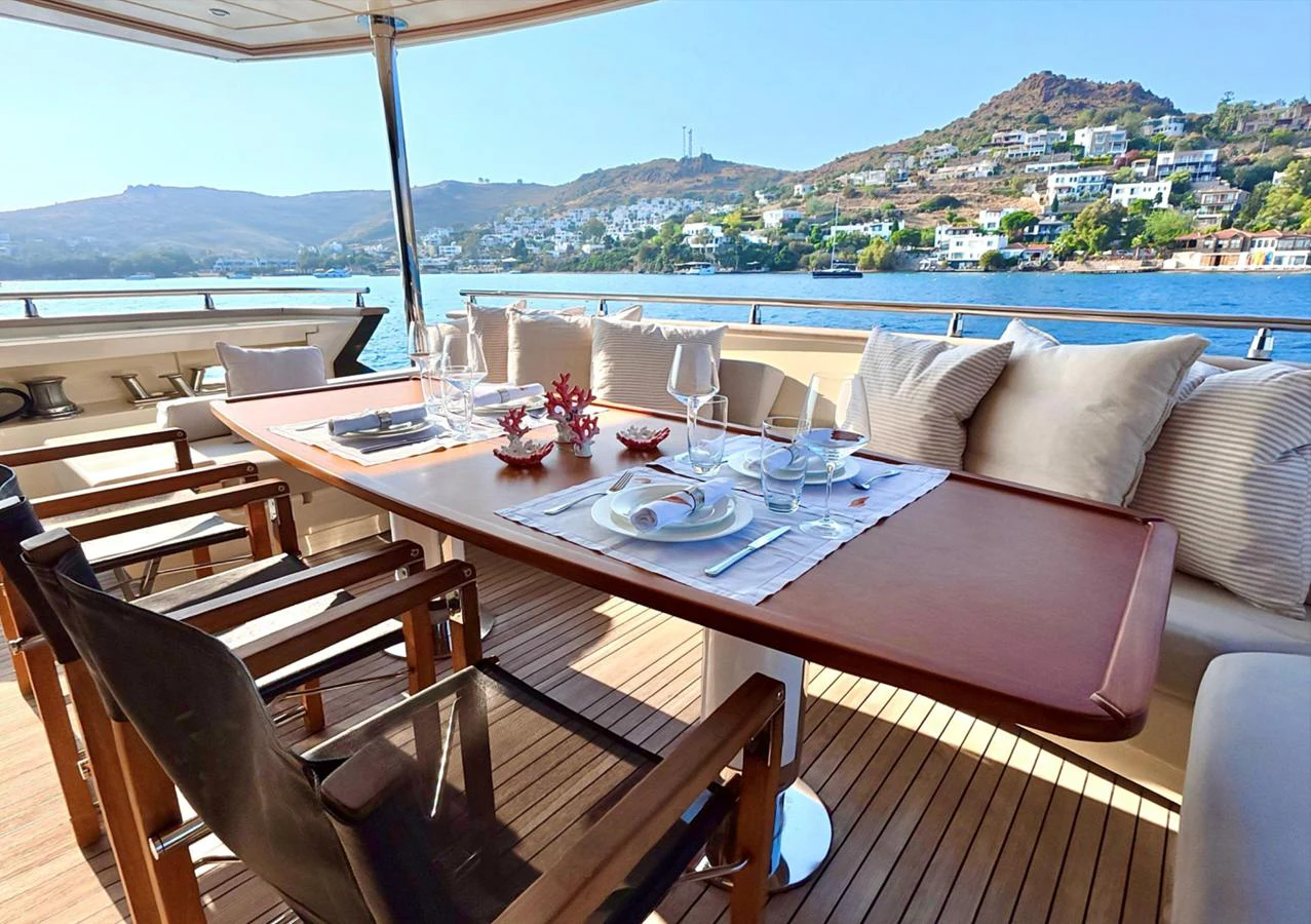 The aft deck features an elegant dining area with a stunning view of the coastline. aboard RIVA 115 Yacht for Sale
