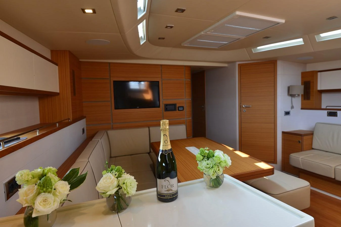 The yacht's interior features a cozy seating area with a table, complemented by elegant decor and a bottle of champagne. aboard MAZARIN 72 CRUISER RACER Yacht for Sale