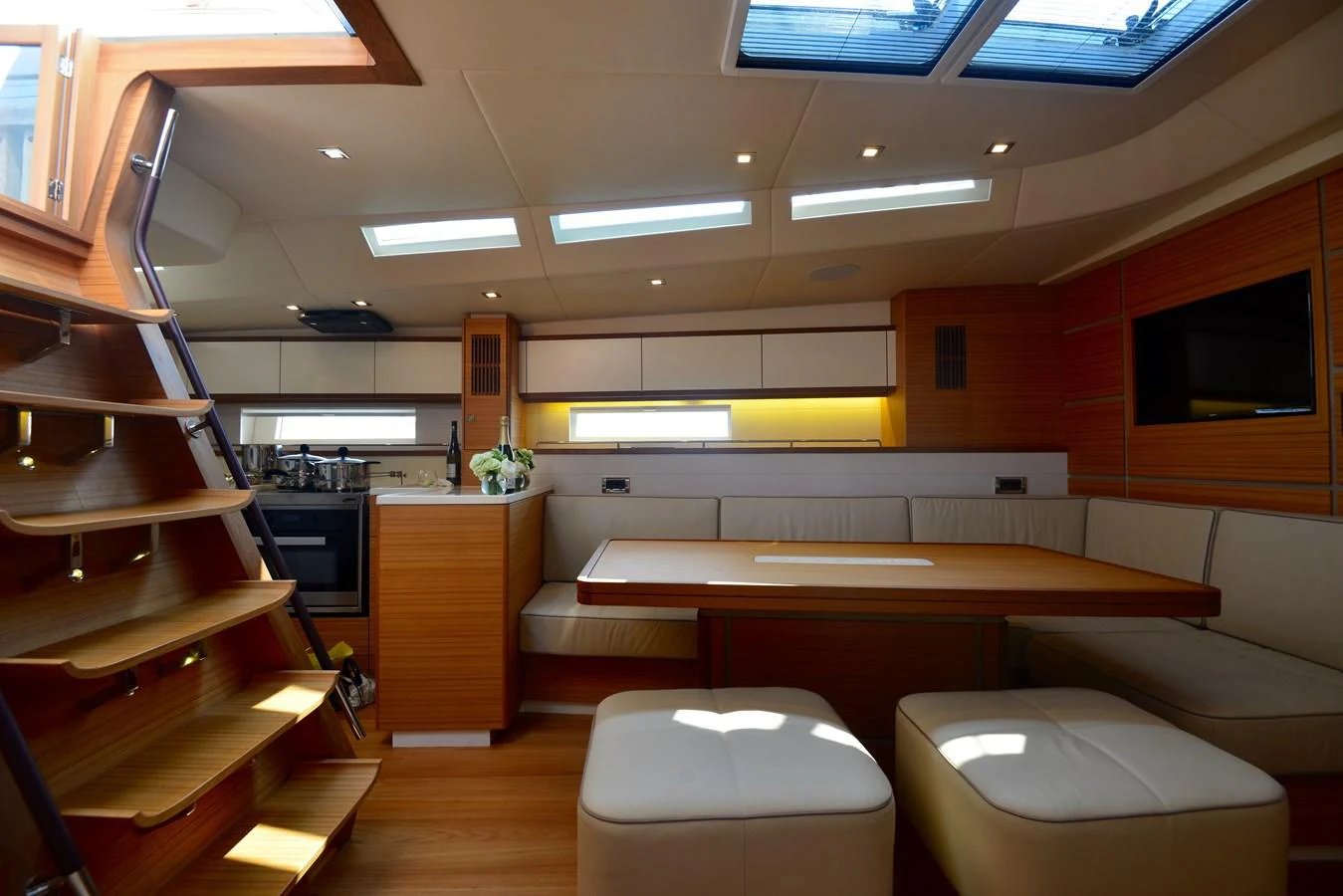 The yacht's salon features a cozy seating area with a dining table and ample natural light from overhead skylights. aboard MAZARIN 72 CRUISER RACER Yacht for Sale