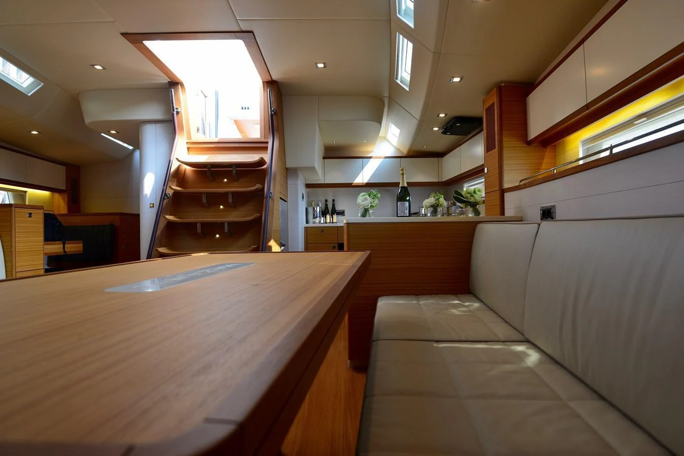 The yacht's salon features a cozy seating area with a wooden table and ample natural light. aboard MAZARIN 72 CRUISER RACER Yacht for Sale