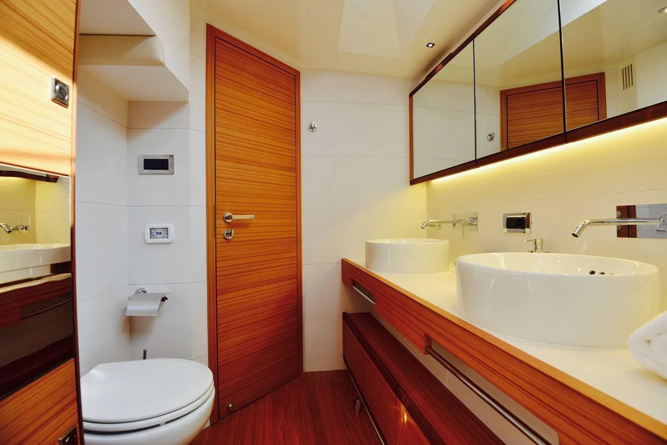 A modern yacht bathroom featuring sleek wooden accents and dual sinks. aboard MAZARIN 72 CRUISER RACER Yacht for Sale