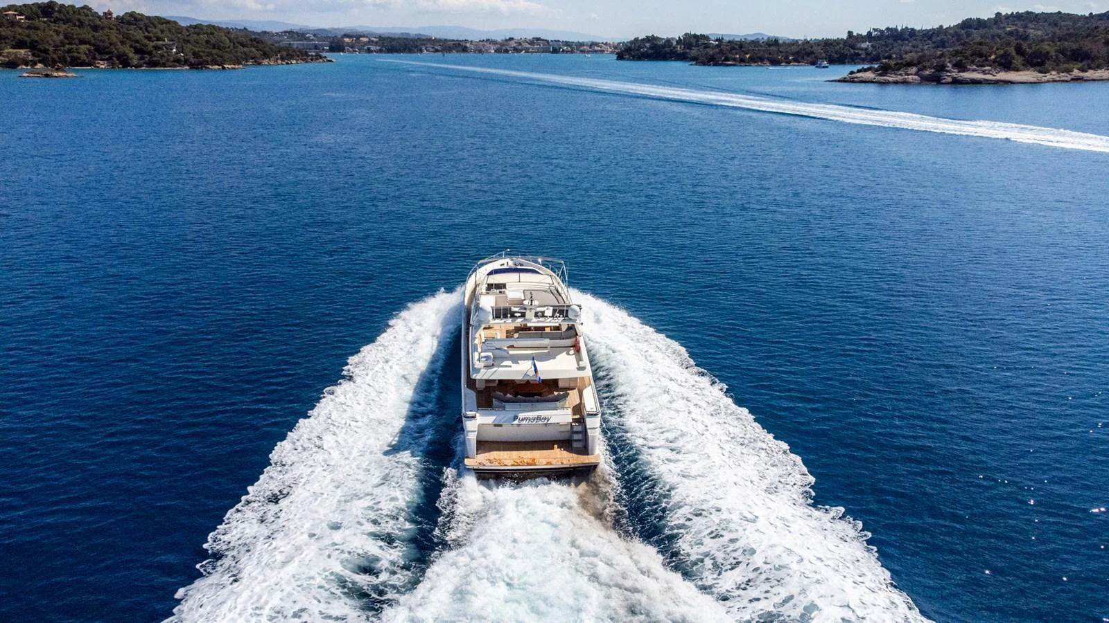 A luxurious yacht cruises through pristine blue waters, leaving a trail of white wake behind. aboard PUMABAY Yacht for Sale