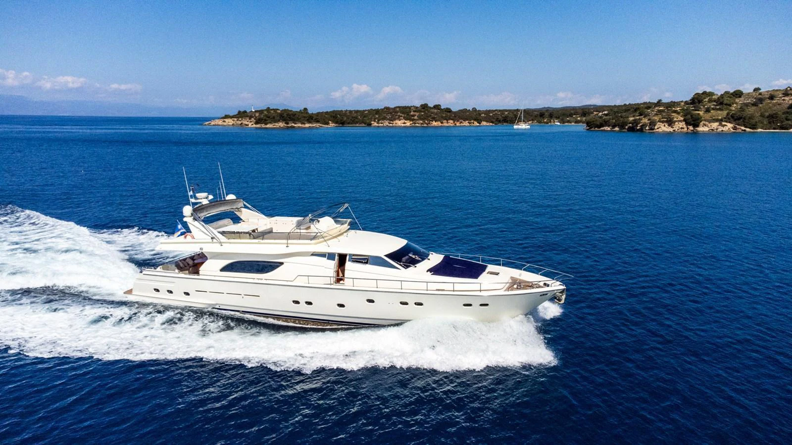 A sleek yacht cruises through clear blue waters against a backdrop of distant islands. aboard PUMABAY Yacht for Sale