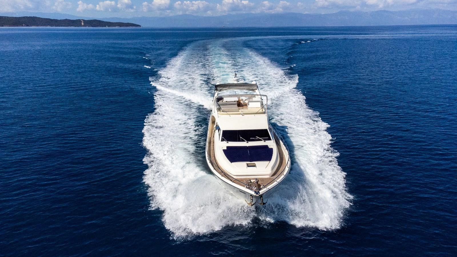 A sleek yacht cruising swiftly on open blue waters, leaving a trail of white wake behind. aboard PUMABAY Yacht for Sale