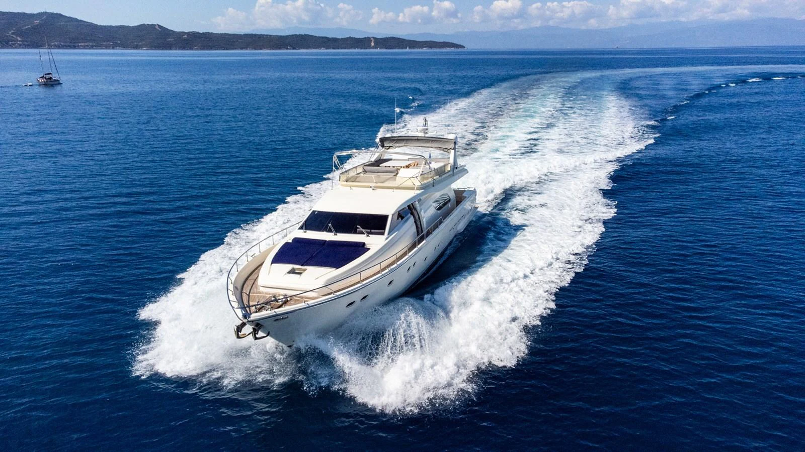 A sleek yacht cruises through clear blue waters, leaving a trail of white wake behind. aboard PUMABAY Yacht for Sale