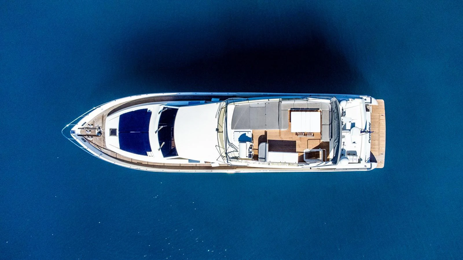 A sleek yacht is captured from an aerial view, showcasing its elegant design and spacious deck areas. aboard PUMABAY Yacht for Sale