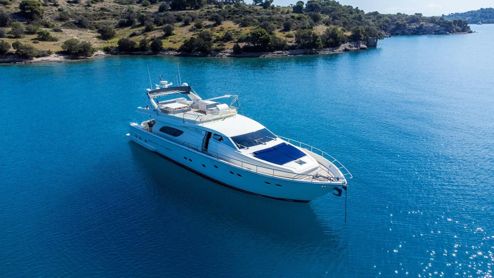 A sleek yacht glides gracefully on calm, clear blue waters near a scenic coastline. aboard PUMABAY Yacht for Sale