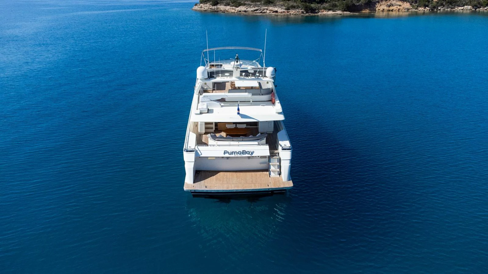 A luxurious yacht is anchored in serene blue waters, showcasing its spacious aft deck. aboard PUMABAY Yacht for Sale