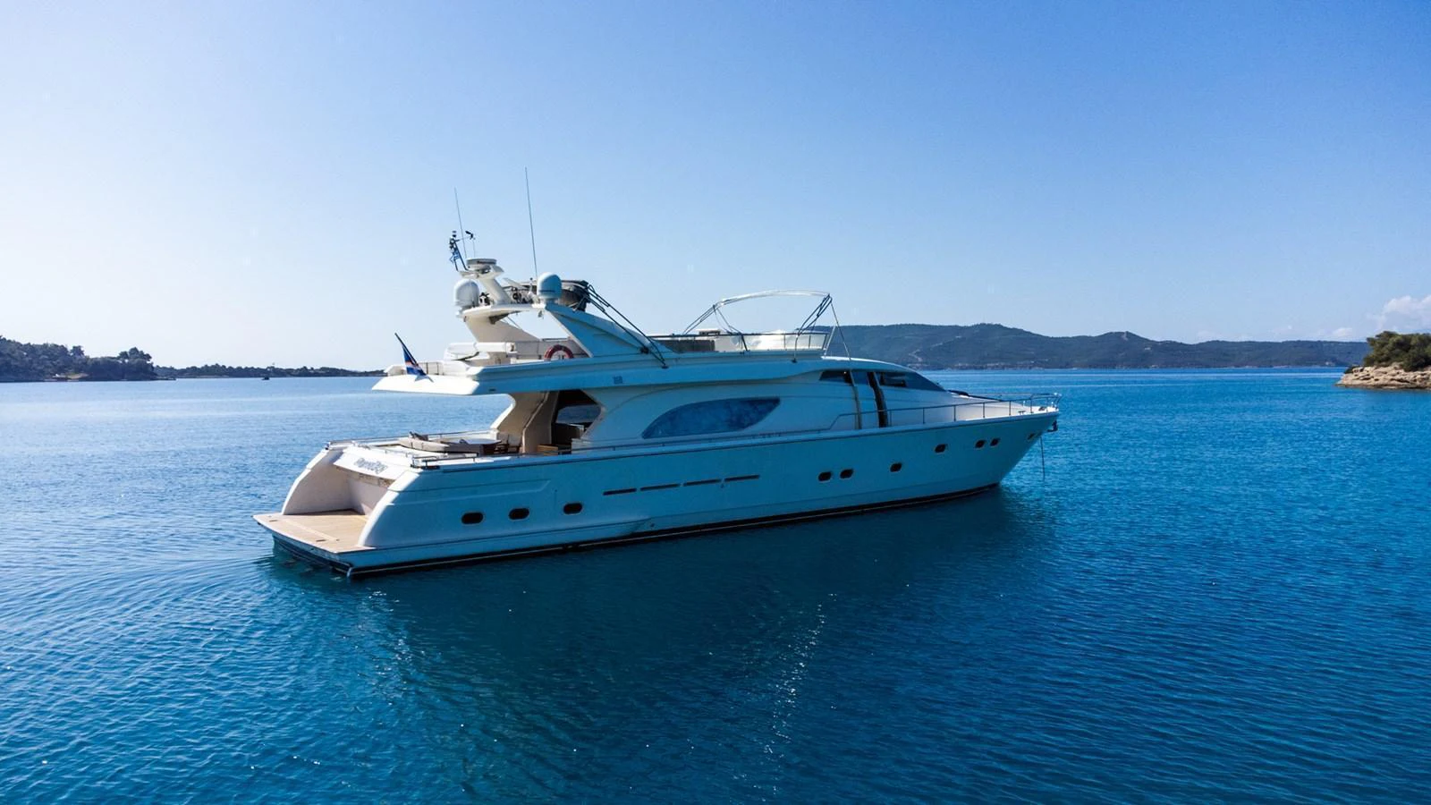 A sleek yacht glides gracefully on calm blue waters under a clear sky. aboard PUMABAY Yacht for Sale