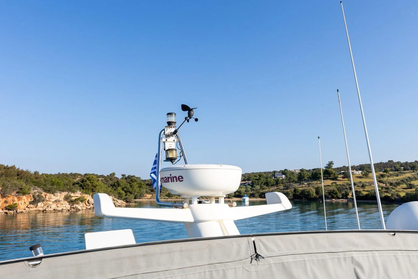 A close-up view of the yacht's radar and communication equipment against a serene coastal backdrop. aboard PUMABAY Yacht for Sale