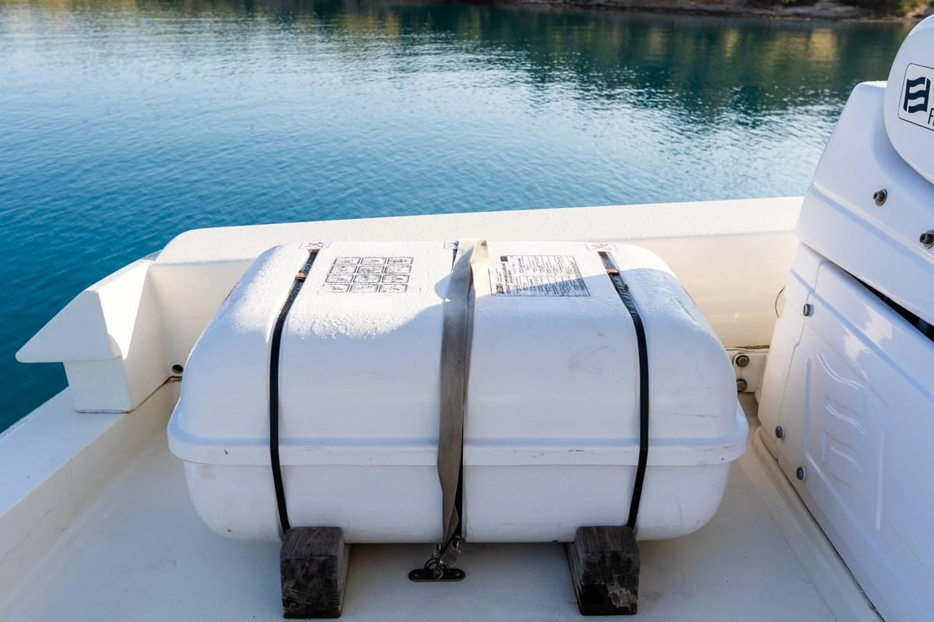 A close-up view of a secured white storage container on the deck of a yacht, with calm blue water in the background. aboard PUMABAY Yacht for Sale