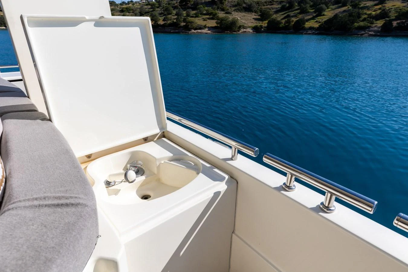 A close-up view of a built-in sink on the yacht's deck, with a serene water backdrop. aboard PUMABAY Yacht for Sale