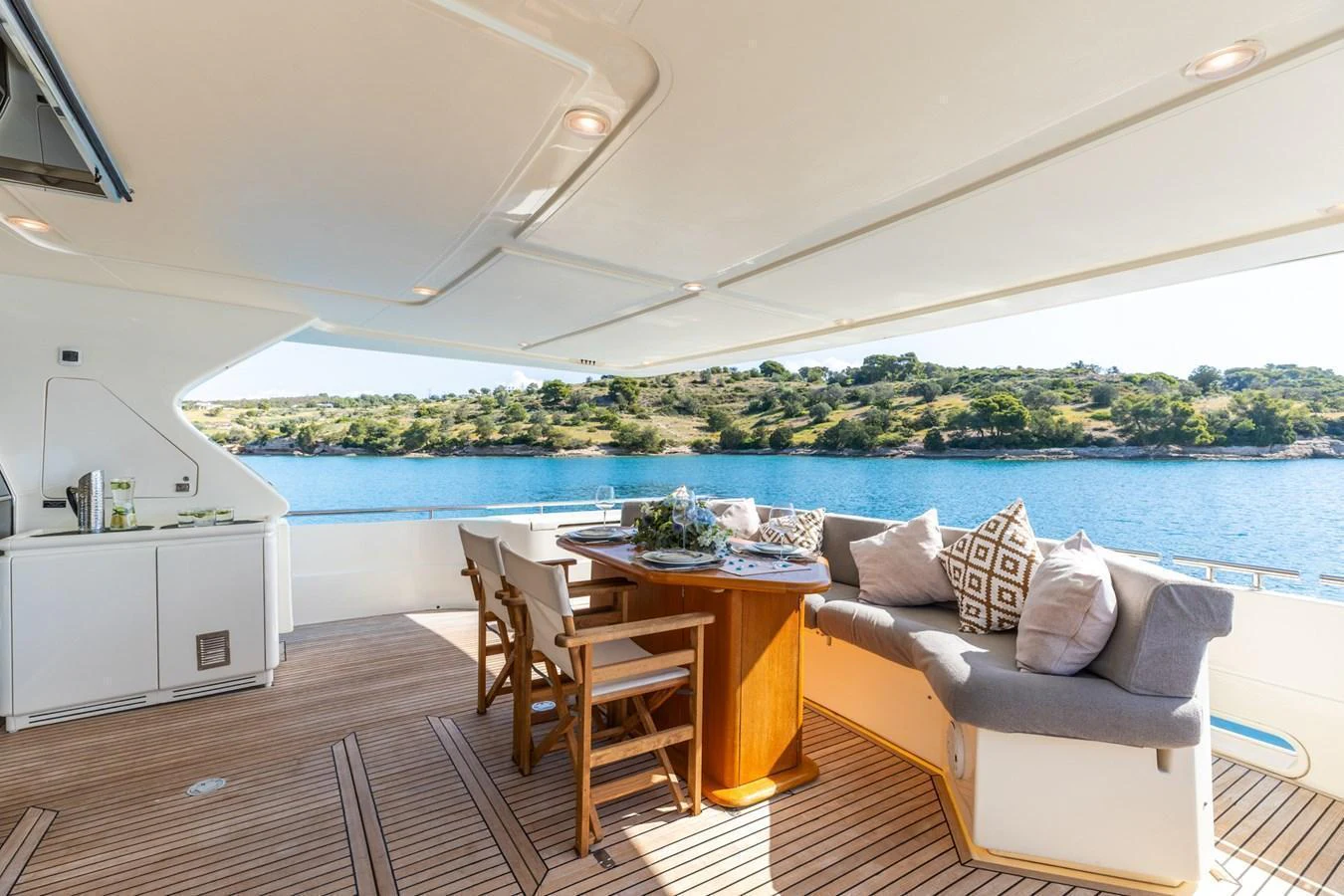 The aft deck features a comfortable seating area with a dining table, perfect for enjoying meals with a view of the water. aboard PUMABAY Yacht for Sale