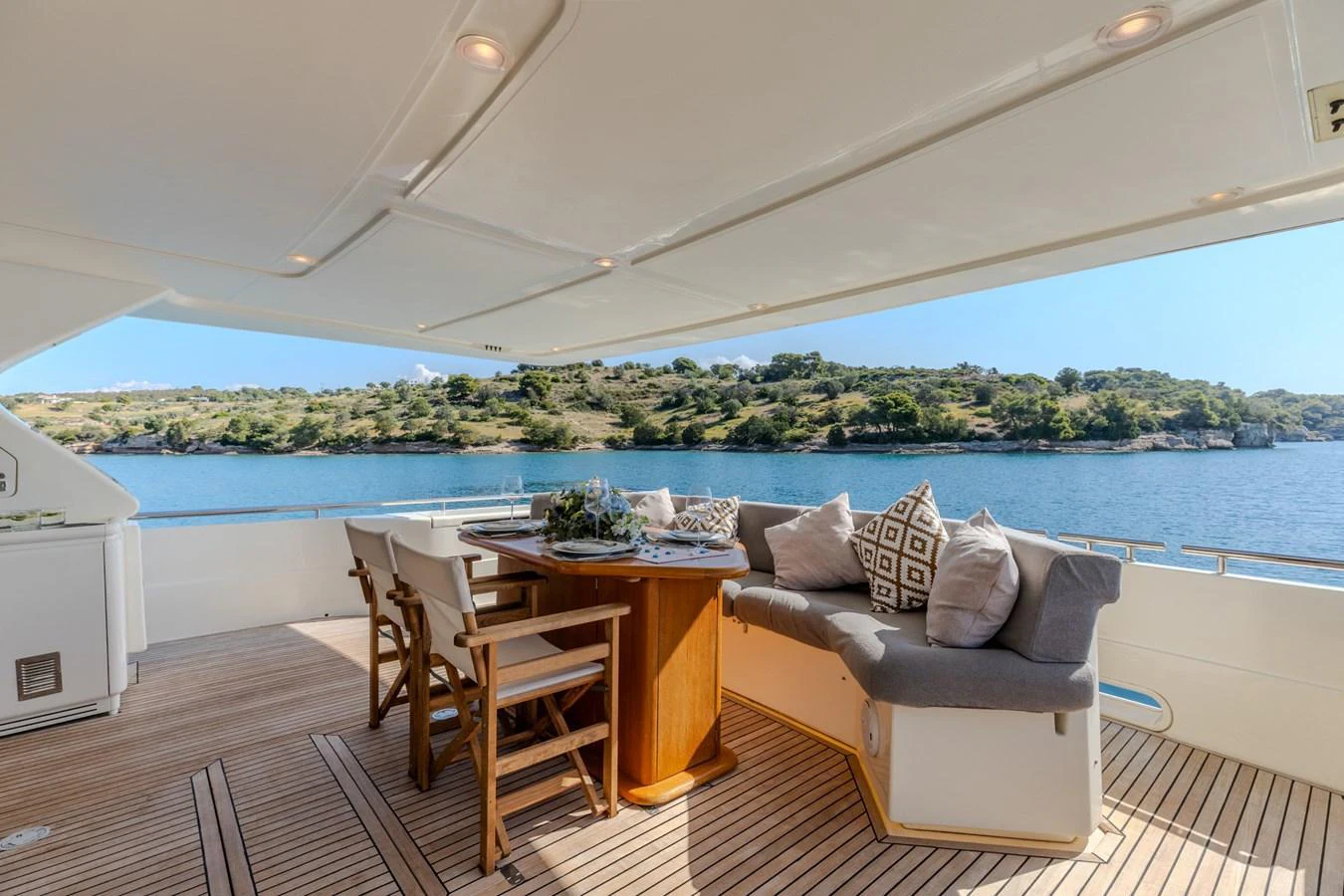 The aft deck features a comfortable seating area with a dining table, perfect for enjoying meals with a view of the water. aboard PUMABAY Yacht for Sale