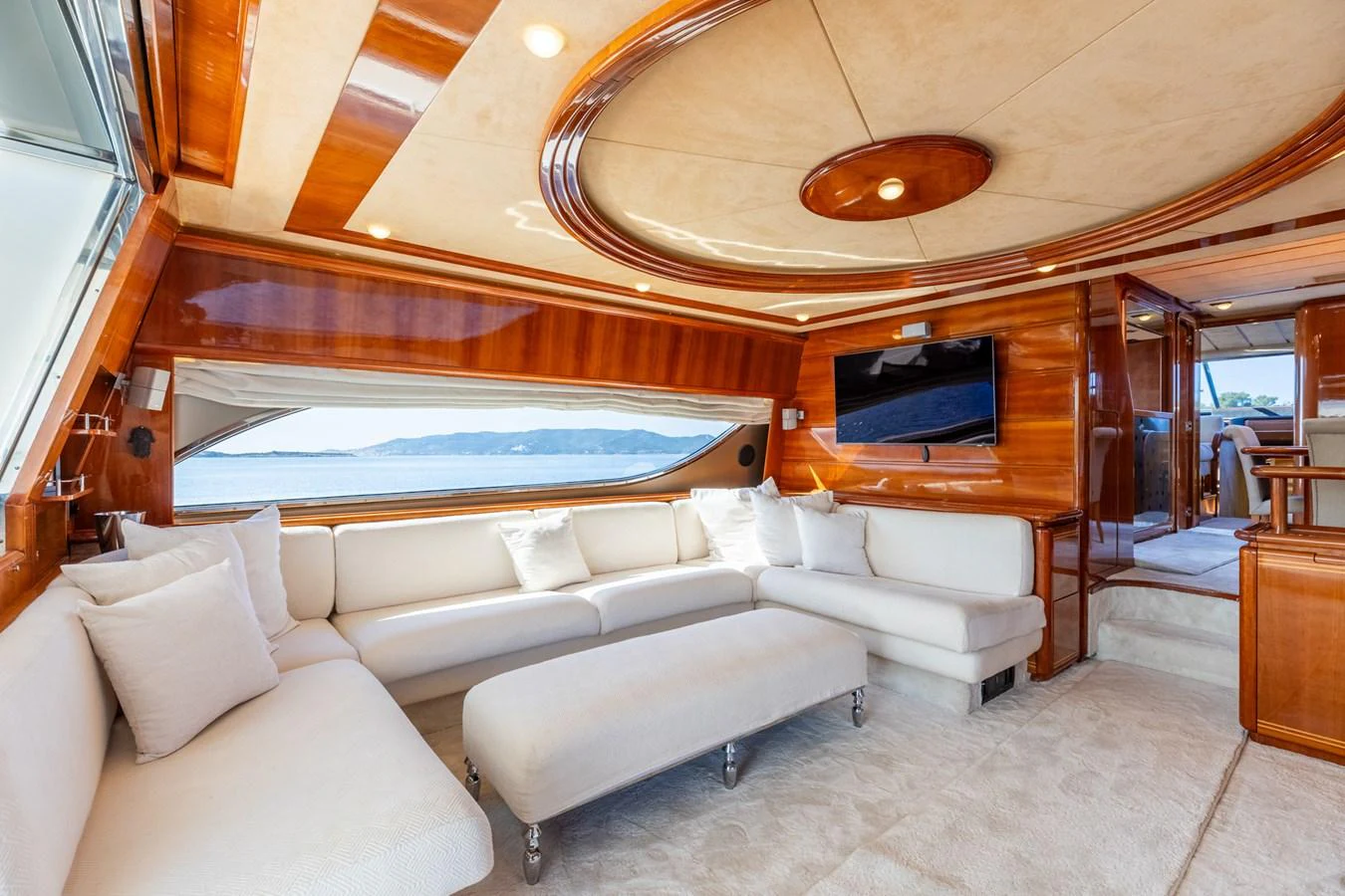 The salon features plush white seating, rich wood accents, and large windows offering stunning views. aboard PUMABAY Yacht for Sale